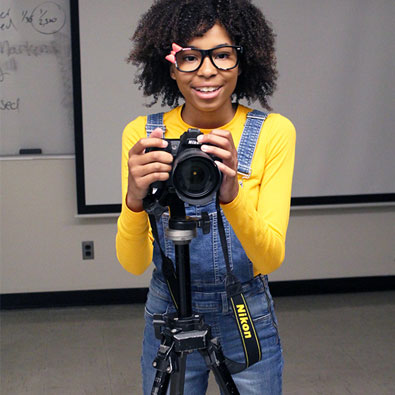 student standing with a camera stand