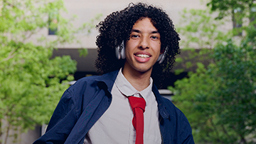 FIT student in headphones wearing a red tie and denim