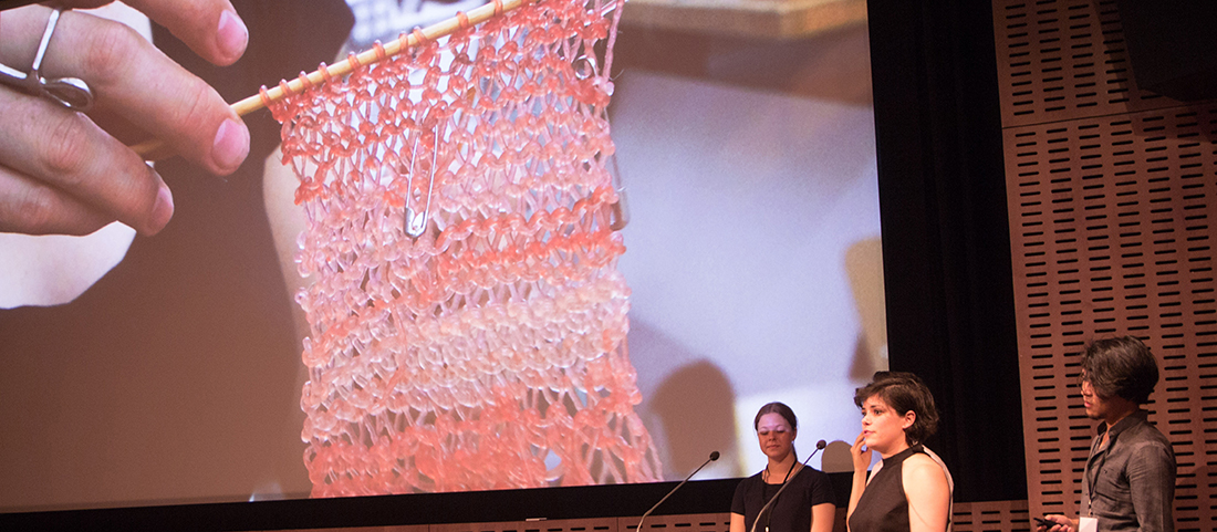 A demonstration from the BioDesign Challenge. A hand is holding up a knitted piece made from algae.