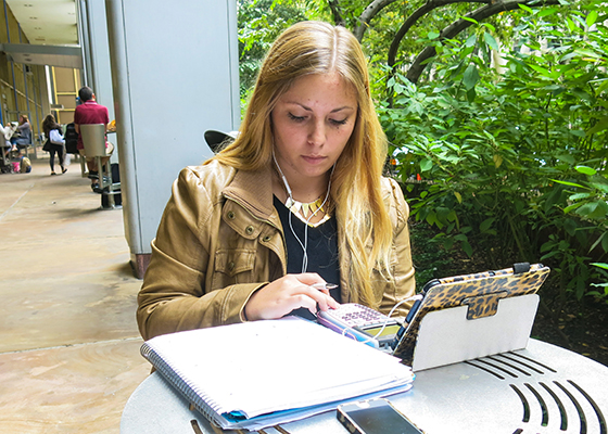 student working on a laptop at one of F i t's outdoor tables