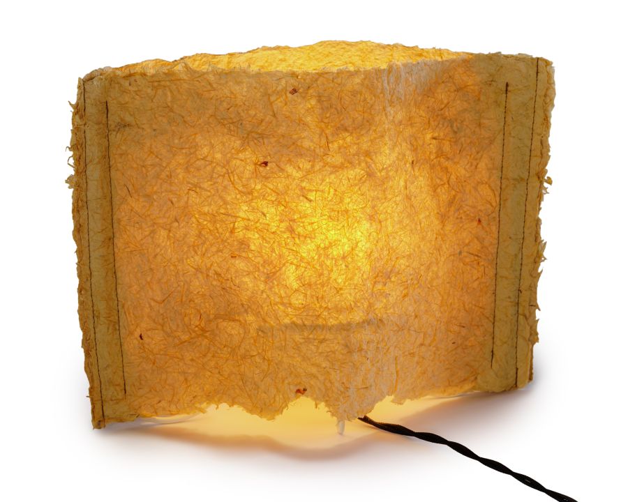 a glowing lamp producing warm yellow tone as it passes through the lampshade. the lampshade is made of natural fibers creating variation in light quality as it come through more transparent and opaque areas of the material.