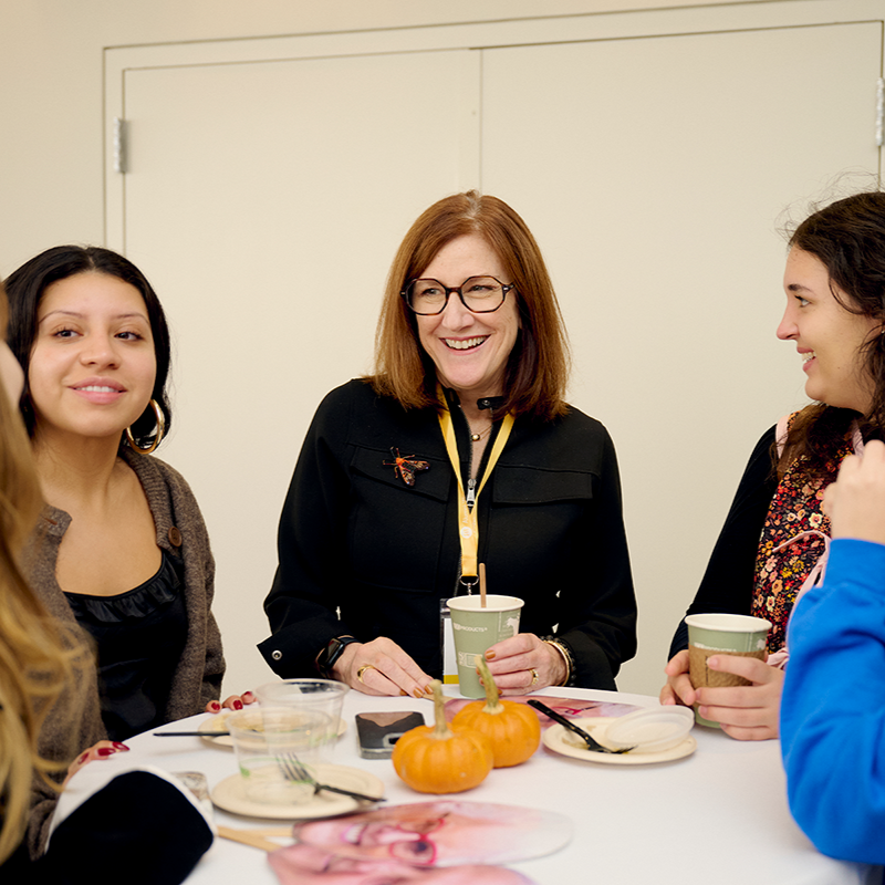 a group of students speaking with faculty at a daytime social
