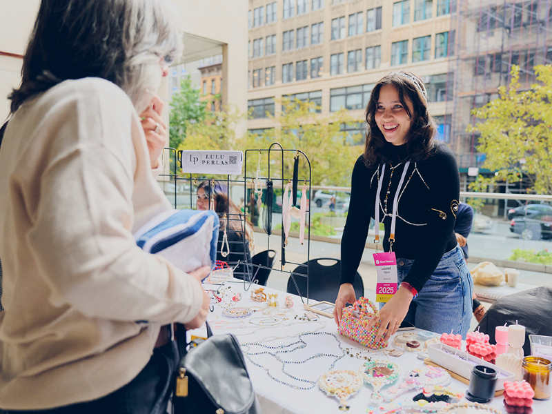 alumni showcasing their wares to a customer at the alumni bazaar