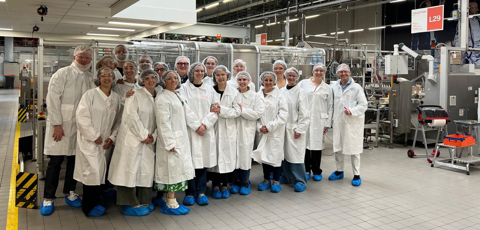 C F M M students in white coats, standing in a laboratory