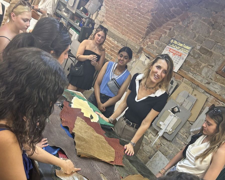 Instructor is speaking to a group of students gathered around the table covered in colored leather samples
