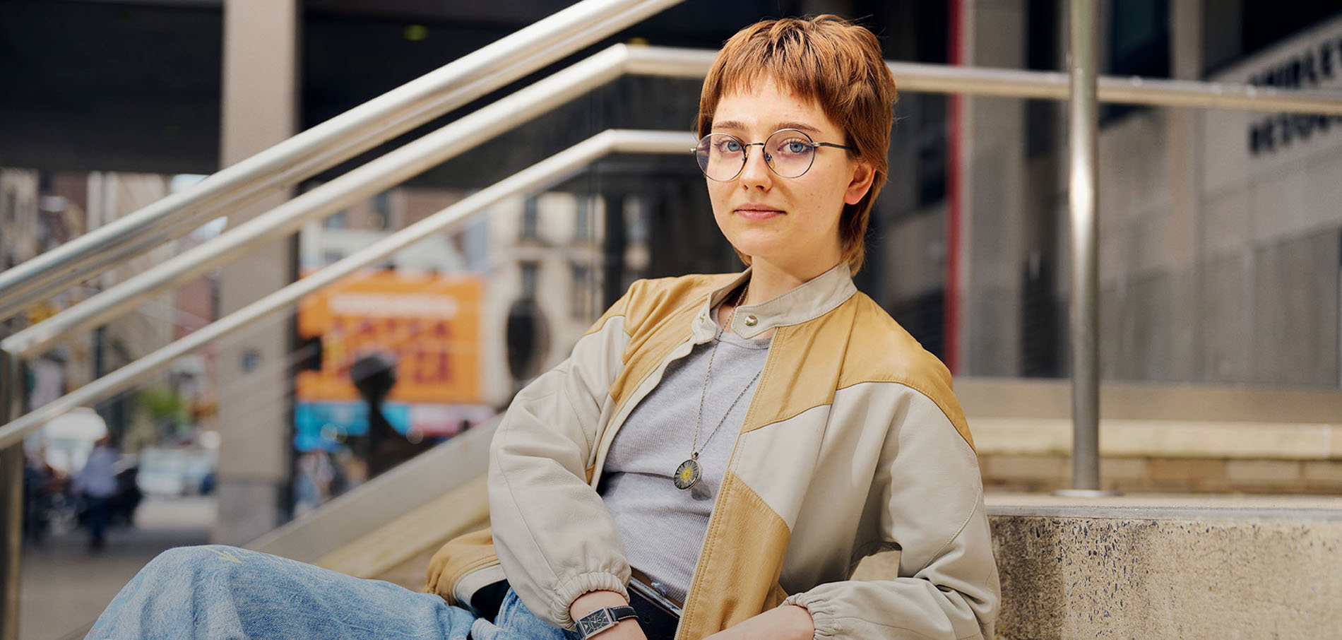 FIT student sitting on stairs in front of Goodman Building