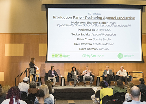 A photo of six people sitting on stage in front of audience