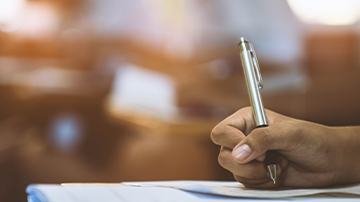 hand holding a pen posed for writing on paper 