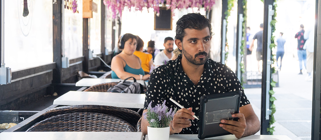 person at outdoor cafe learning online with iPad