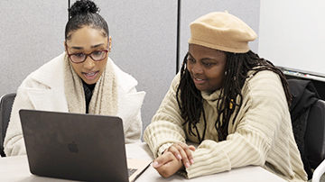 writing studio session: two students looking at a computer screen, reading