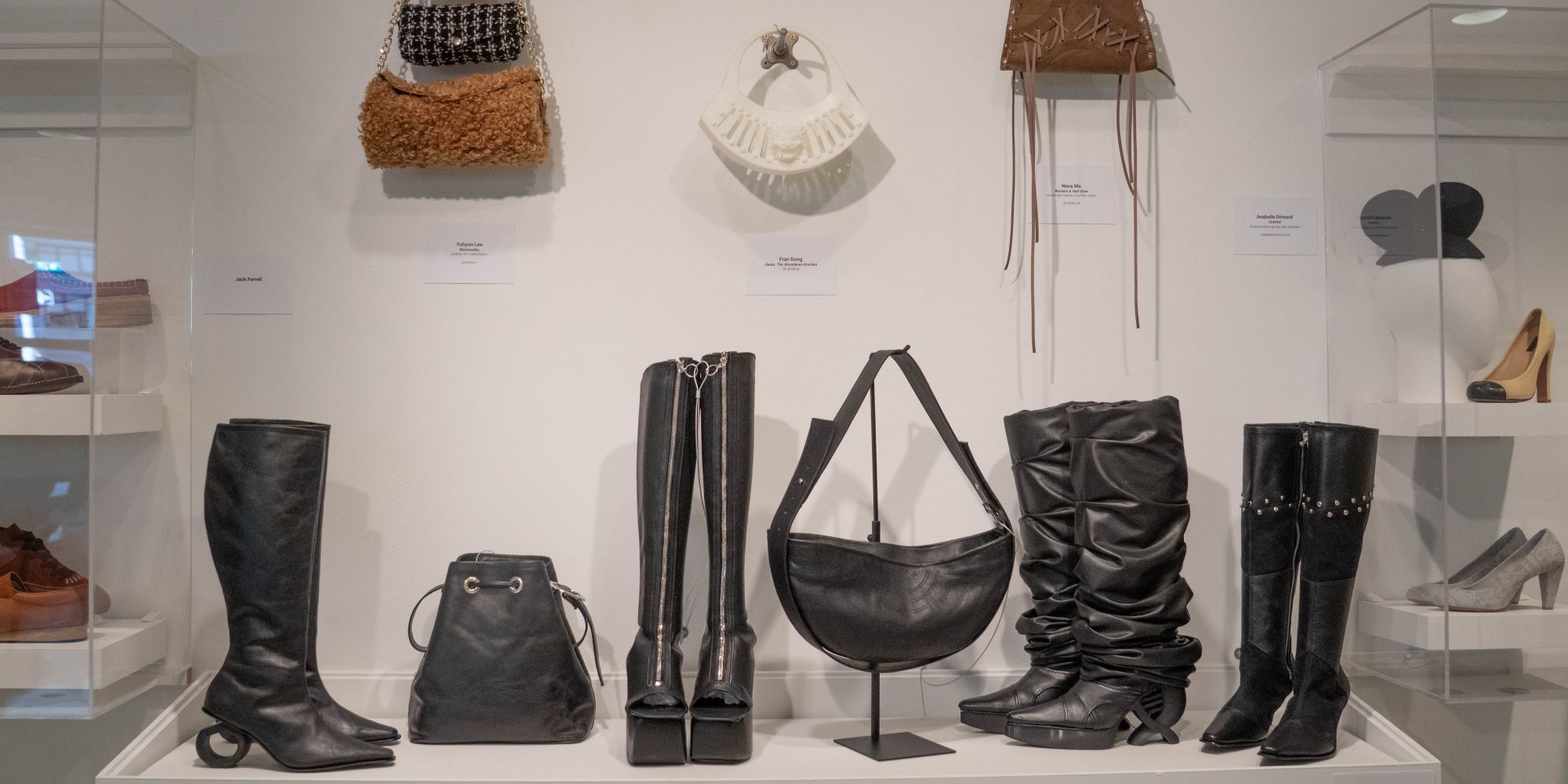 display of several pairs of black platform and heeled boots, pumps, handbags, and sacs in leather and other materials