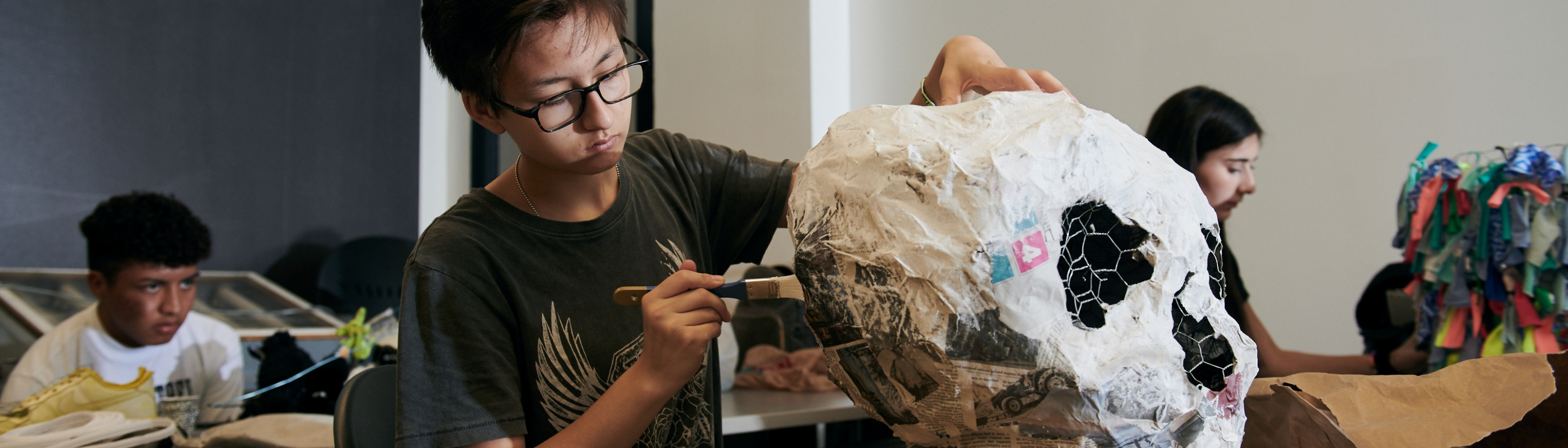 High school student working on a cylindrical sculpture