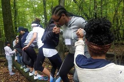 students standing on a log, holding hands