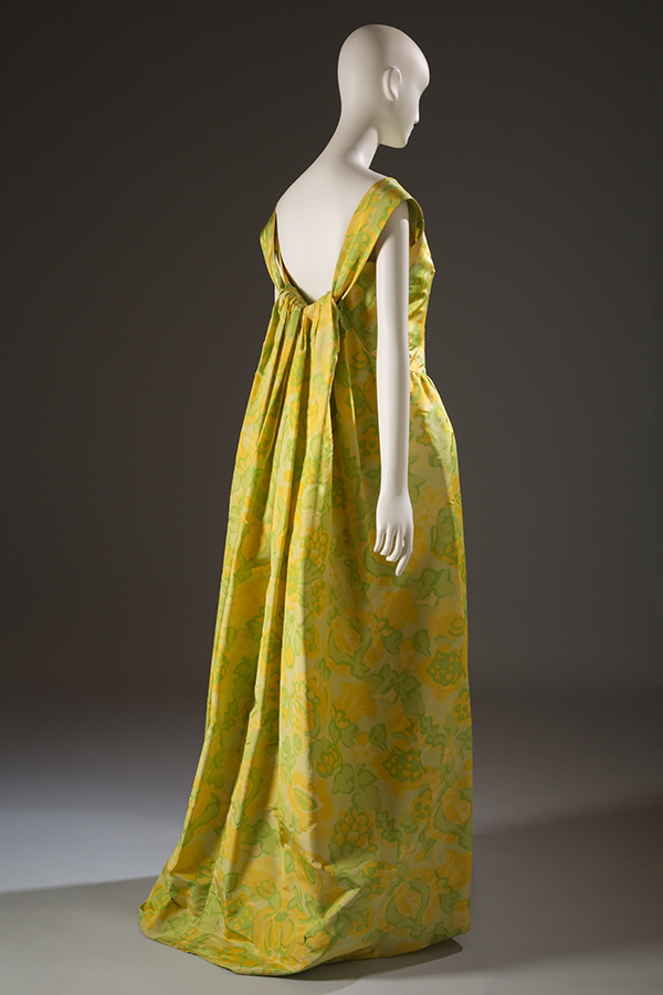 back view of a floor-length evening gown in bright yellow with green floral print