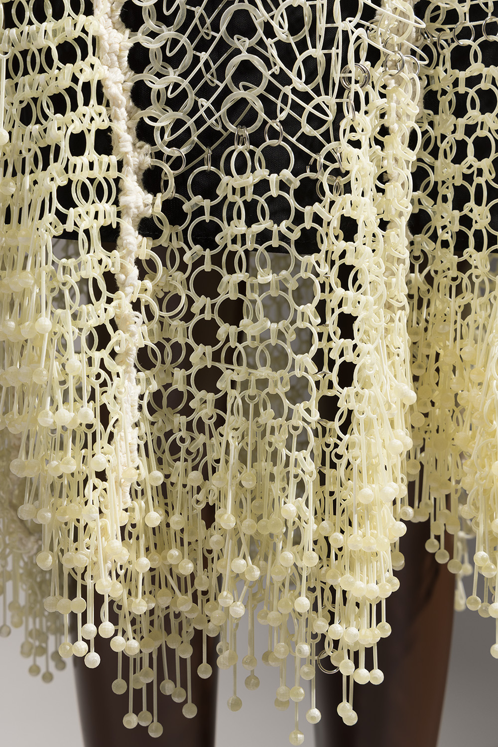 Ohne Titel off-white 3D-printed dress; plastic circular links crocheted with cotton, wide black leather shoulder straps, with black slip underneath. 