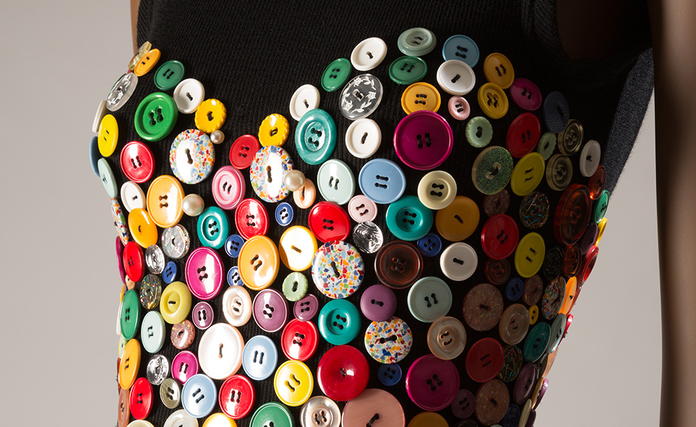 Detail of Patrick Kelly dress with colorful buttons forming a hear on a black knit dress