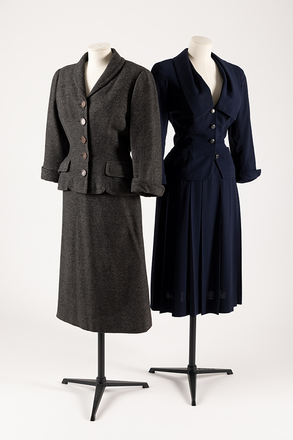two wool women's suits on mannequins. One grey, one black