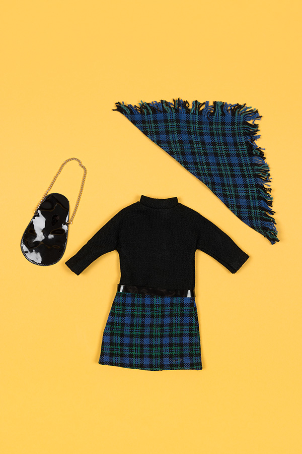 doll's ensemble flat lay featuring a black turtleneck, blue plaid skirt with matching scarf, and a black purse