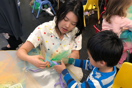 child and teacher doing crafts at a table