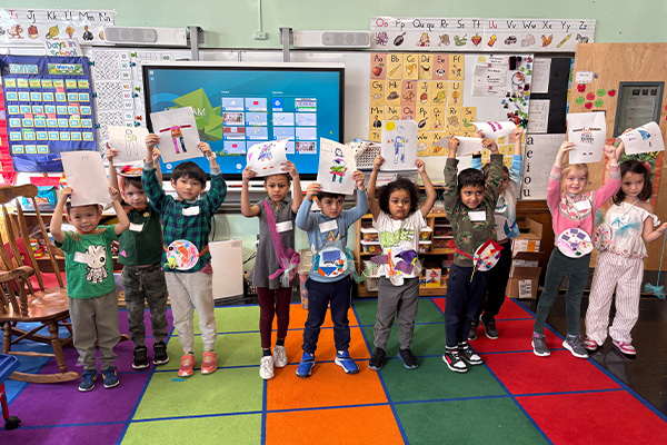 a group of kindergarden students holding up their artwork