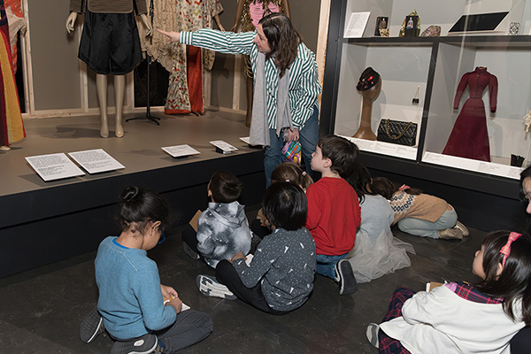 Melissa Marra-Alvarez guiding kindergraden students through an interactive tour of Fashioning Wonder