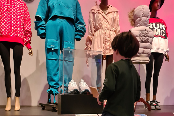 kindergarden student looking at cased shoes in Fresh, Fly, Fabulous: 50 Years of Hip Hop Style installation