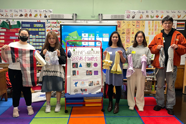 FIT students holding up examples of sleeves as part of a presentation for kindergarden students