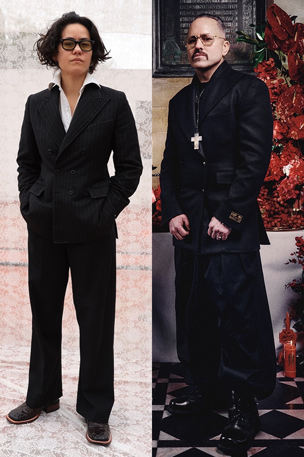 barbara sanchez-kane wearing a black suit against a white lace backdrop and willy chavarria in a black jacket and baggy white pants styled with a cross necklace and a red antharium installation behind him