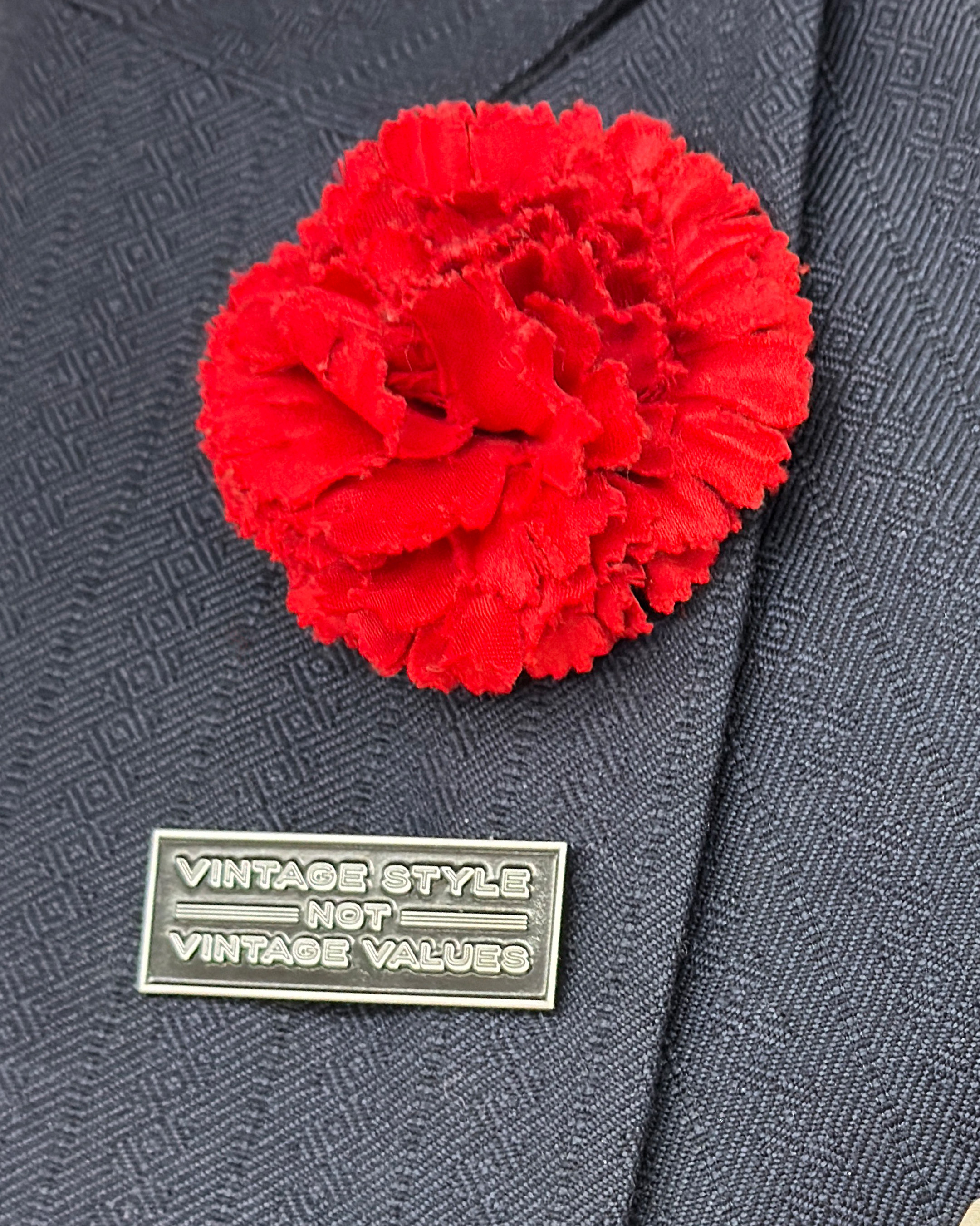 Detail of a red carnation made of fabric and a pin that says Vintage Style not Vintage Values