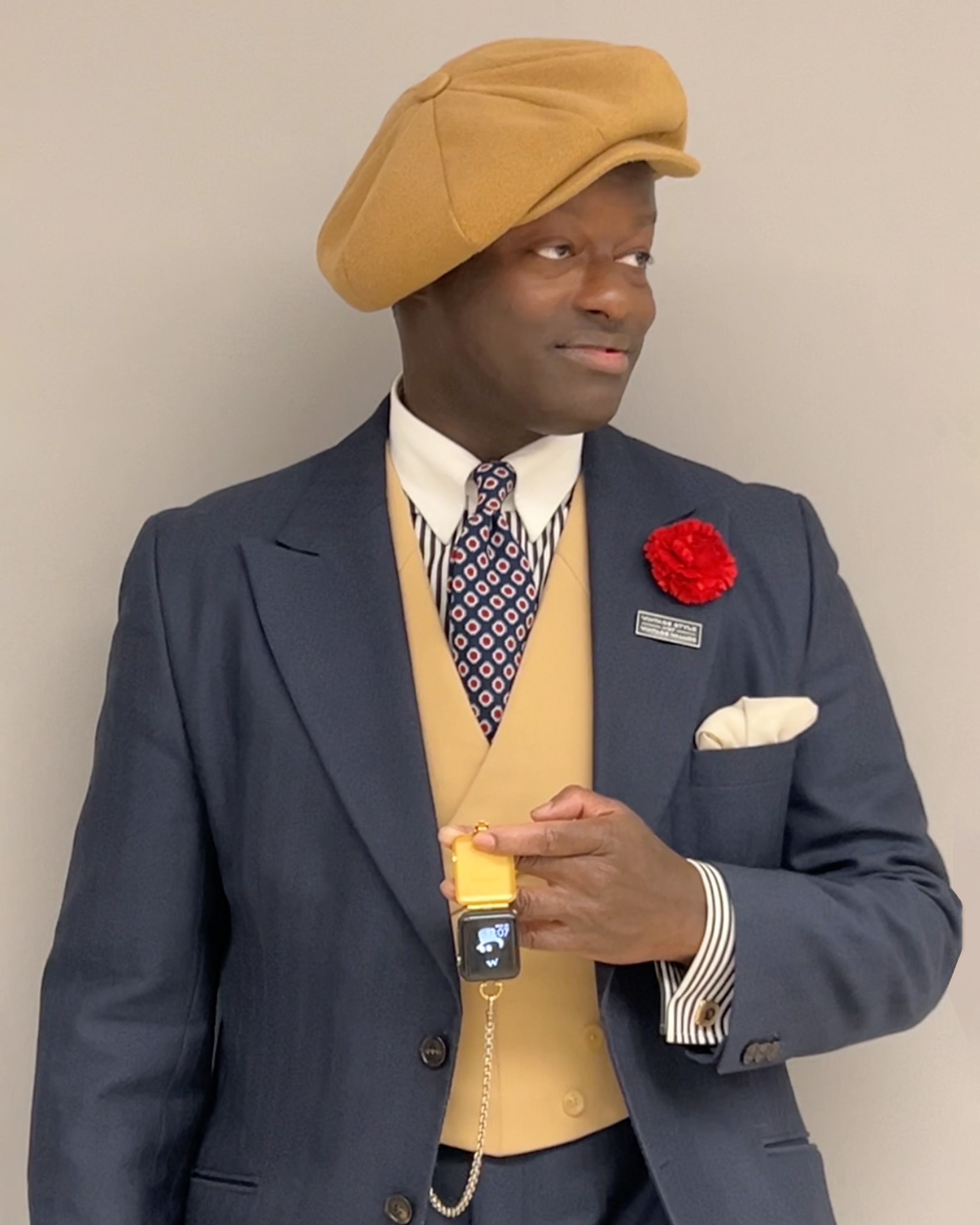 Close shot of Dandy looking to the side while holding a golden/brass pocketwatch holder for his Apple Watch