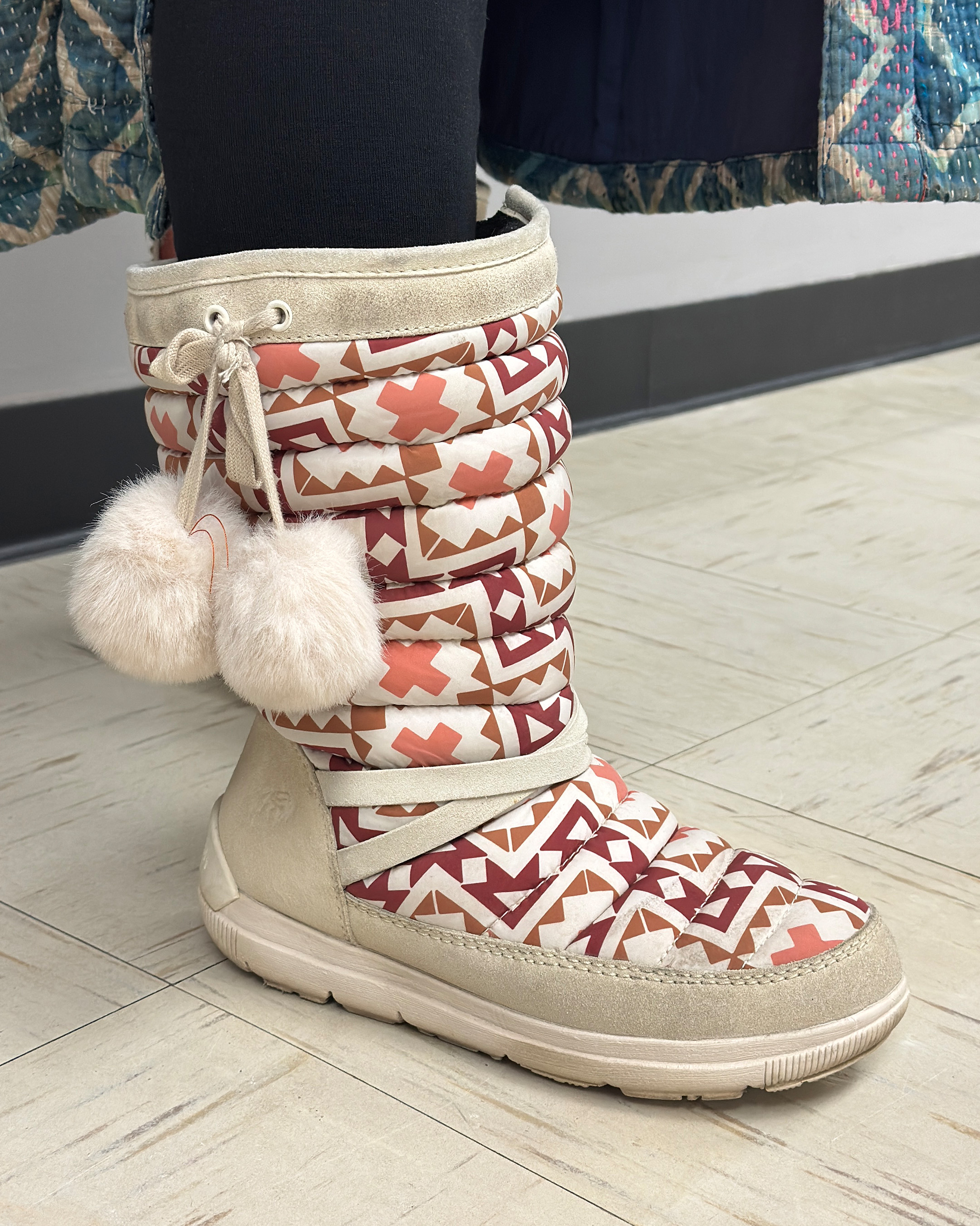 Detail of cream and red Manitoba Mukluk boots in geometric pattern with white pom poms