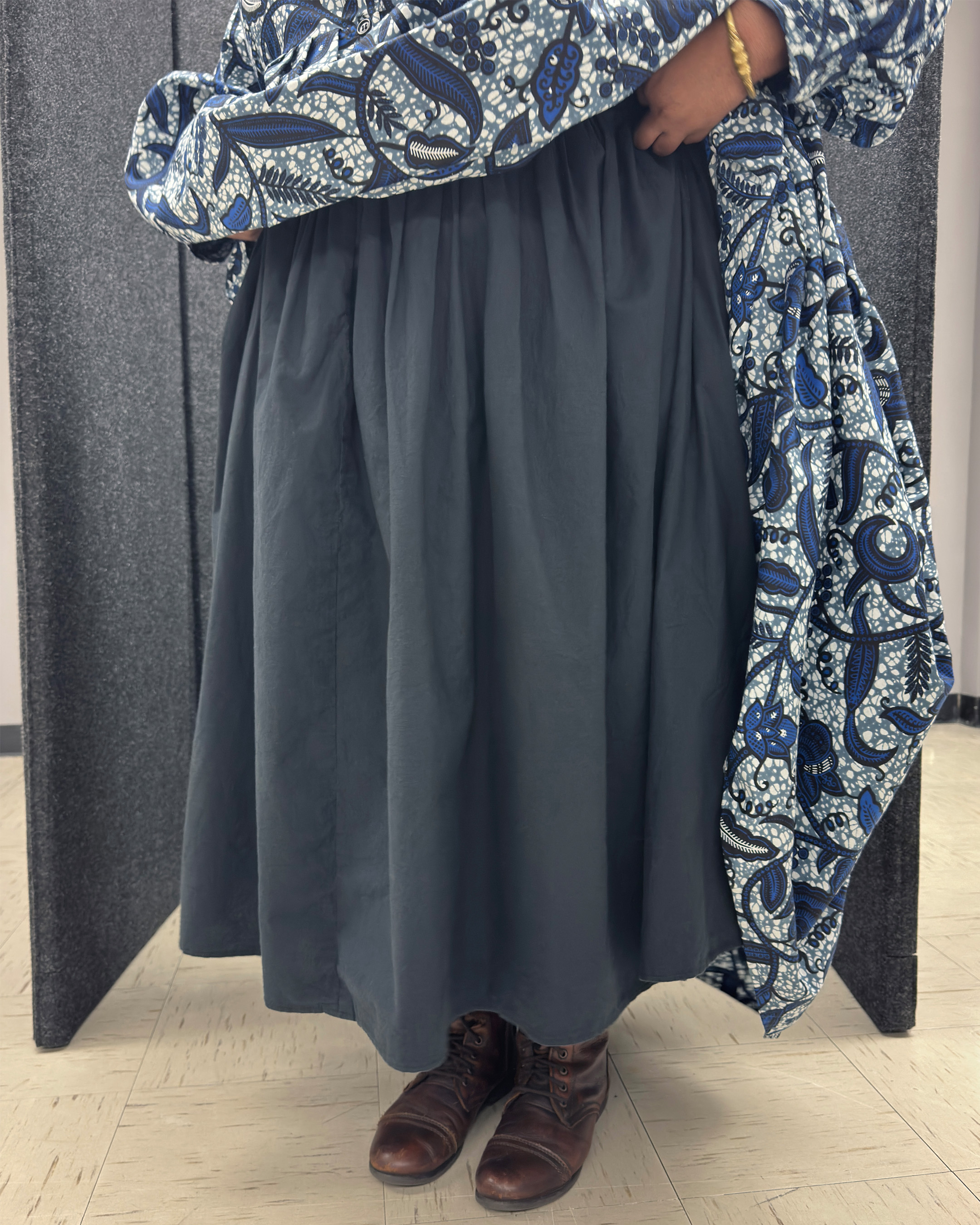 Cheyney lifting her blue dress to reveal a gray under petticoat and her brown boots
