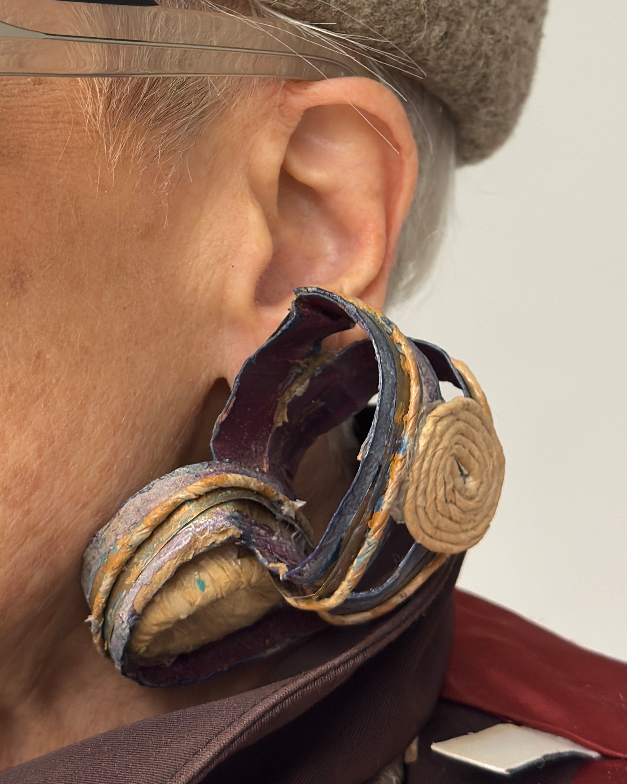 Detail of Debra's earrings: interlocking circles made of toilet paper rolls, embellished with paint and decorative yarn