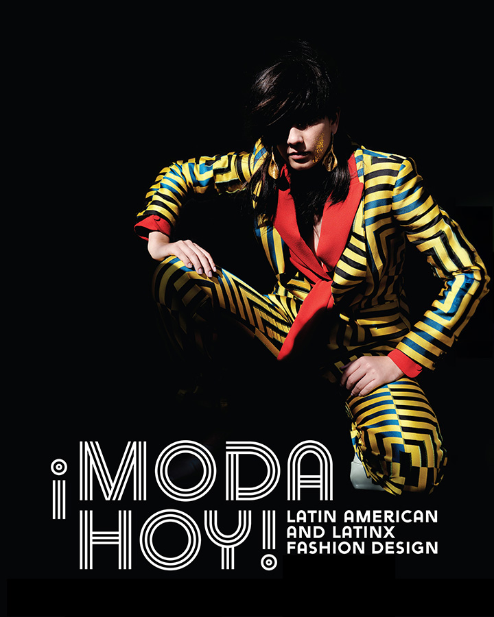 masculine model in a yellow pant suit with green geometric pattern and red trim. text reads, "¡Moda Hoy! Latin American and Latinx Fashion Design"