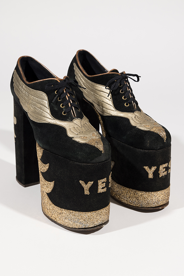 Man’s black suede platform shoes with gold leather wings and gold YES letters in gold glitter on front of platform