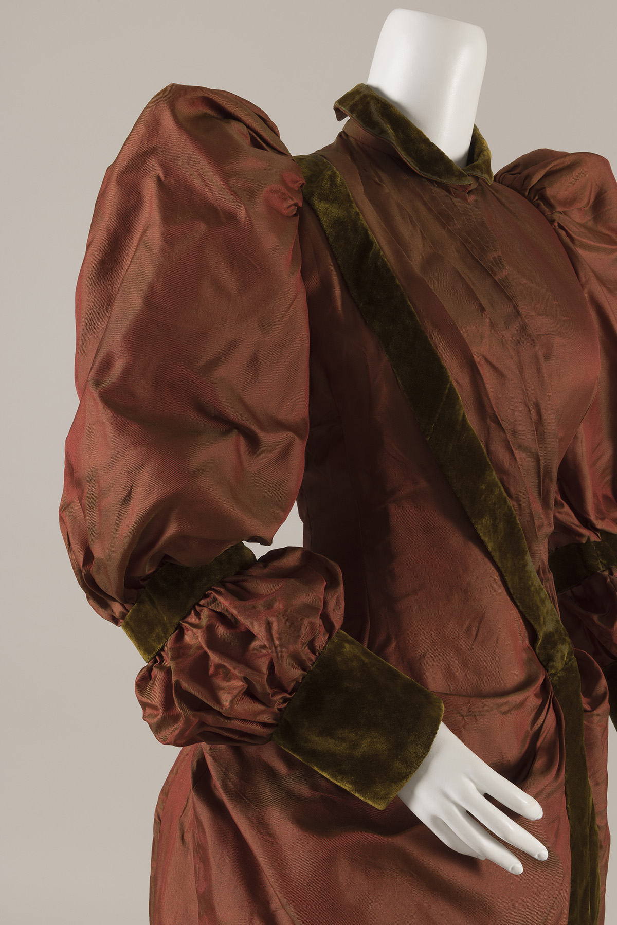 A voluminous silk sleeve with a puff at the shoulder and over the forearm defined by velvet bands positioned below the elbow and at the wrist.