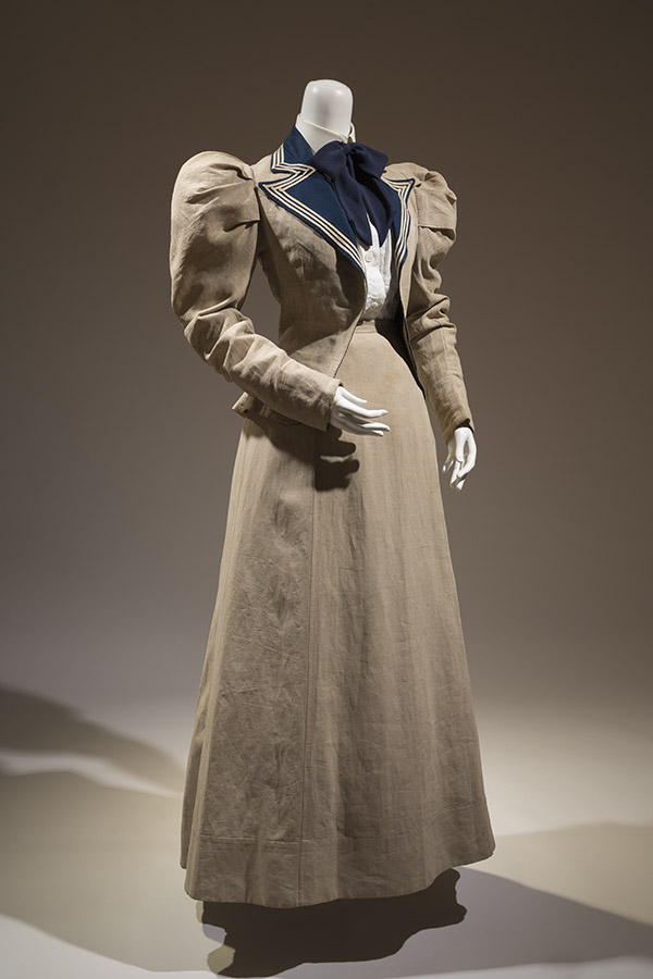 Natural linen summer suit of jacket with puffed shoulders and navy blue lapels, floor length skirt